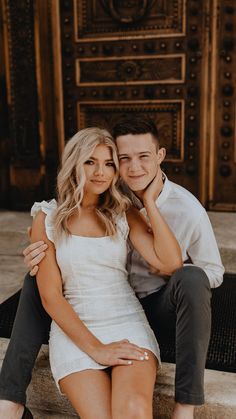 a man and woman sitting next to each other on the steps in front of a building