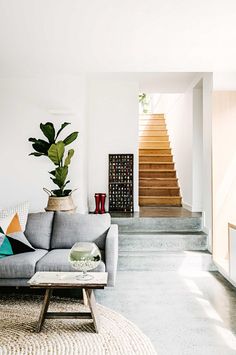 an image of a living room with stairs and plants on the table in front of it