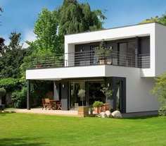 a modern house in the middle of a lush green yard