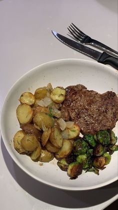 a white plate topped with steak and potatoes