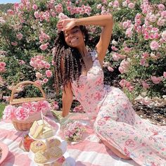 a woman sitting on top of a blanket next to a picnic table filled with food