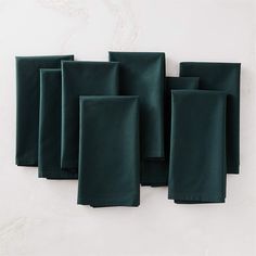 dark green napkins laid out on top of each other in front of a white wall