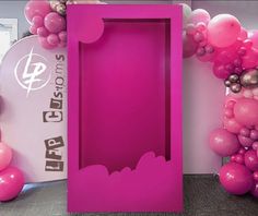 a pink box with balloons in the shape of bats is next to a balloon arch