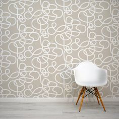 a white chair sitting in front of a wall with an intricate pattern on the wall