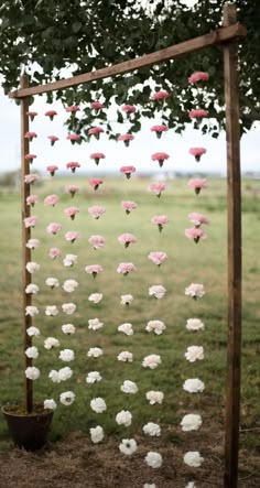 an outdoor wedding ceremony with flowers hanging from the branches and petals on the ground, in front of a field