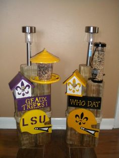 two bird feeders made out of glass bottles with yellow lids and purple letters on them