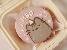 a decorated cookie with a cat on it's face in a cardboard box that says hbd