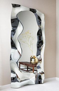 a mirror with an artistic design on the side and a table in front of it