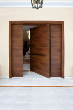 an open wooden door with a light fixture on the ceiling and tiled flooring in front of it