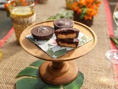 three chocolate covered pastries on a plate with flowers and wine glasses in the background