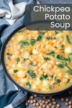 chickpea and potato soup in a black bowl on a blue towel next to peas