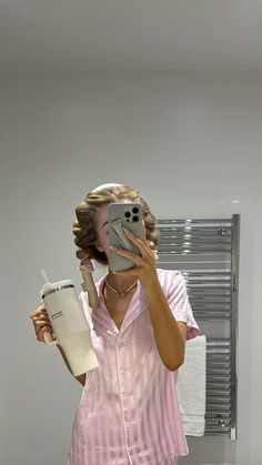 a woman taking a selfie with her cell phone in front of her face and holding a cup