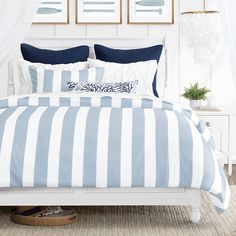 a bed with blue and white striped comforter in a bedroom next to two pictures on the wall