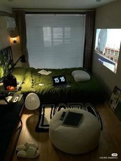 a room with a bed, laptop and other items on the floor in front of a large window