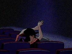 a woman is sitting in an empty theater with her arms outstretched and legs bent over the seats