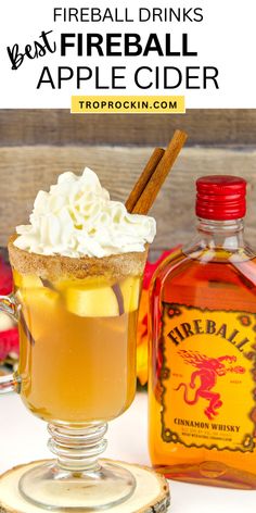 an apple cider with whipped cream and cinnamon on the rim next to a bottle of fireball cider