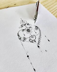 a pen drawing a heart on top of a piece of paper with swirls and dots