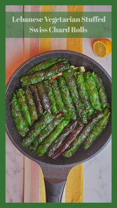 a pan filled with green vegetables on top of a wooden table next to an orange slice