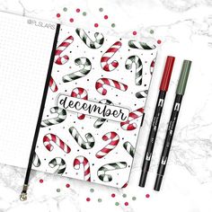 an open notebook with christmas candy canes on it next to two markers and a pen