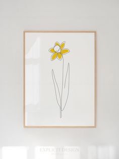 a white wall with a yellow flower in the middle and a wooden frame hanging above it