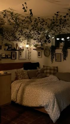 a bed room with a neatly made bed and lots of plants hanging from the ceiling