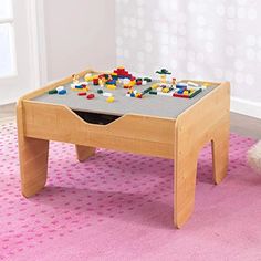 a child's wooden table with legos on it in a pink carpeted room