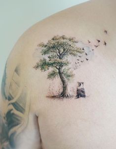 a man with a tree and birds tattoo on his back shoulder is looking at the sky