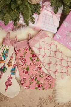 christmas stockings and presents are laid out on the floor next to a tree with pink bows