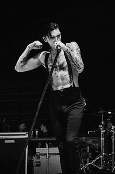 a man with tattoos on his chest standing in front of a microphone and holding a mic