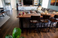 a living room filled with furniture and a large wooden table in front of a tv