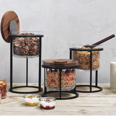 three glass containers filled with food sitting on top of a wooden table next to other items