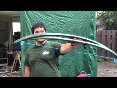 a man is holding an arrow in front of a green tarp