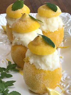 three lemon desserts on a white plate with green leaves