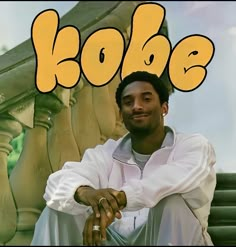 a man sitting on top of a wooden bench next to a sign that says kobe