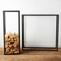 there are two frames on the floor with logs in them and one has a white wall behind it