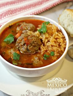 a white bowl filled with meatballs and rice next to a slice of bread on a plate