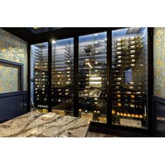 a wine cellar in the middle of a room with glass walls and marble counter tops