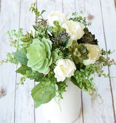 a white vase filled with flowers on top of a wooden table