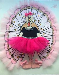 a pink and black turkey costume on top of a white board with gold glitters