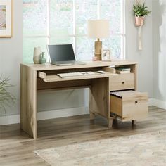 a computer desk with a laptop on top of it next to a lamp and potted plant