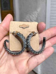 a person holding up a pair of earrings with an octopus design on the front and back