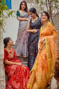 three women in colorful sari sitting on the steps with one woman looking at her