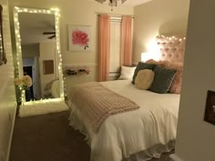 a white bed sitting under a mirror next to a light on a ceiling fan in a bedroom