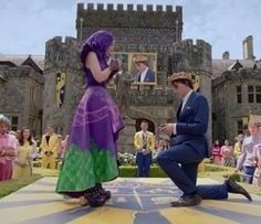 a man kneeling down next to a woman in a purple dress