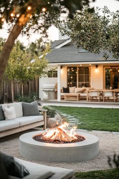 a fire pit sitting in the middle of a yard next to a couch and table