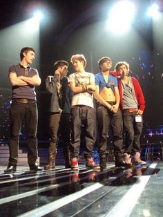 five young men standing on stage with their hands in their pockets