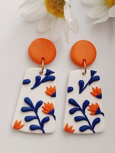 two white and orange earrings with flowers on them