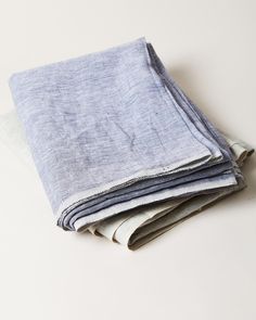 three folded linens are stacked on top of each other, one is white and the other is blue