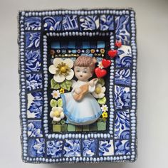 a blue and white tile frame with a little angel holding a heart in it's hand