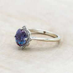 a ring with an oval shaped purple stone surrounded by diamonds